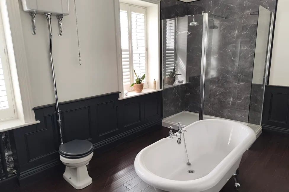 A second roll-top bath, with panelling, shutters and a walk-in shower alongside