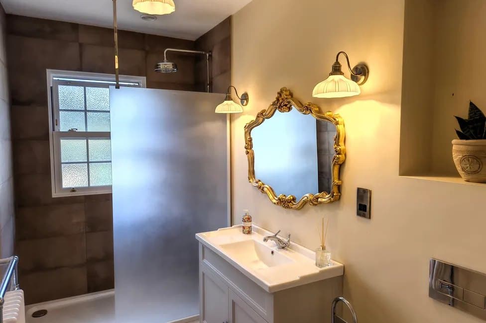 A bathroom with an ornate gilt mirror over a pedestal basin