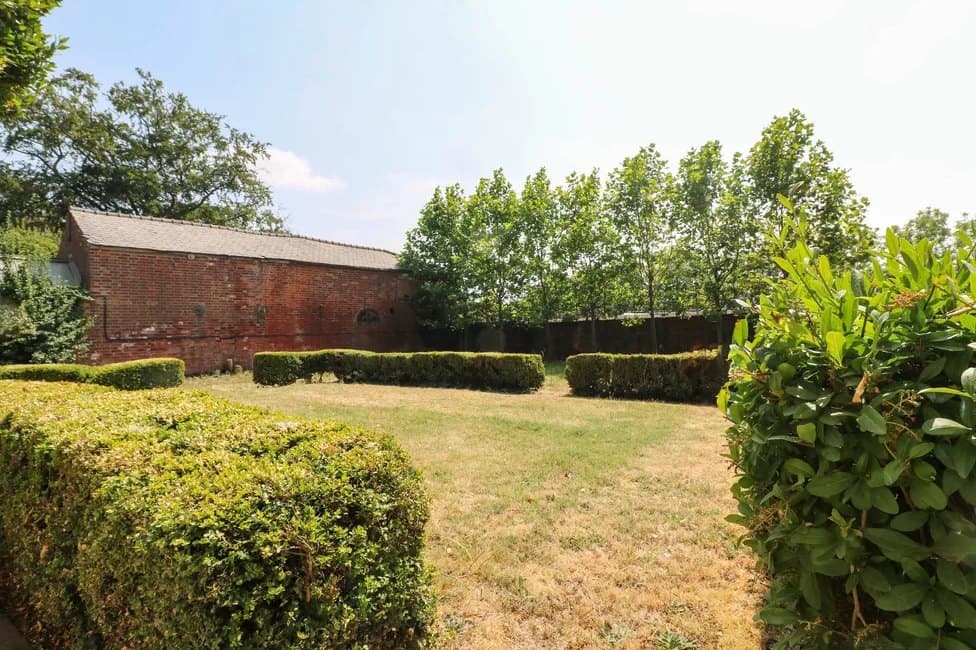 The walled grounds, with clipped hedging and lawn running back from the house