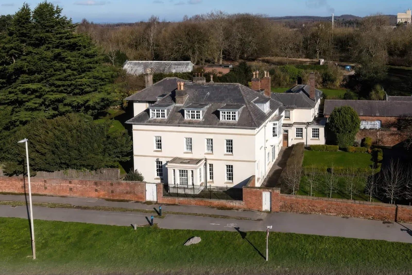 Bardon Hill Manor from the air — a white Georgian manor house set behind a red brick wall, with mature trees and lawned grounds around it